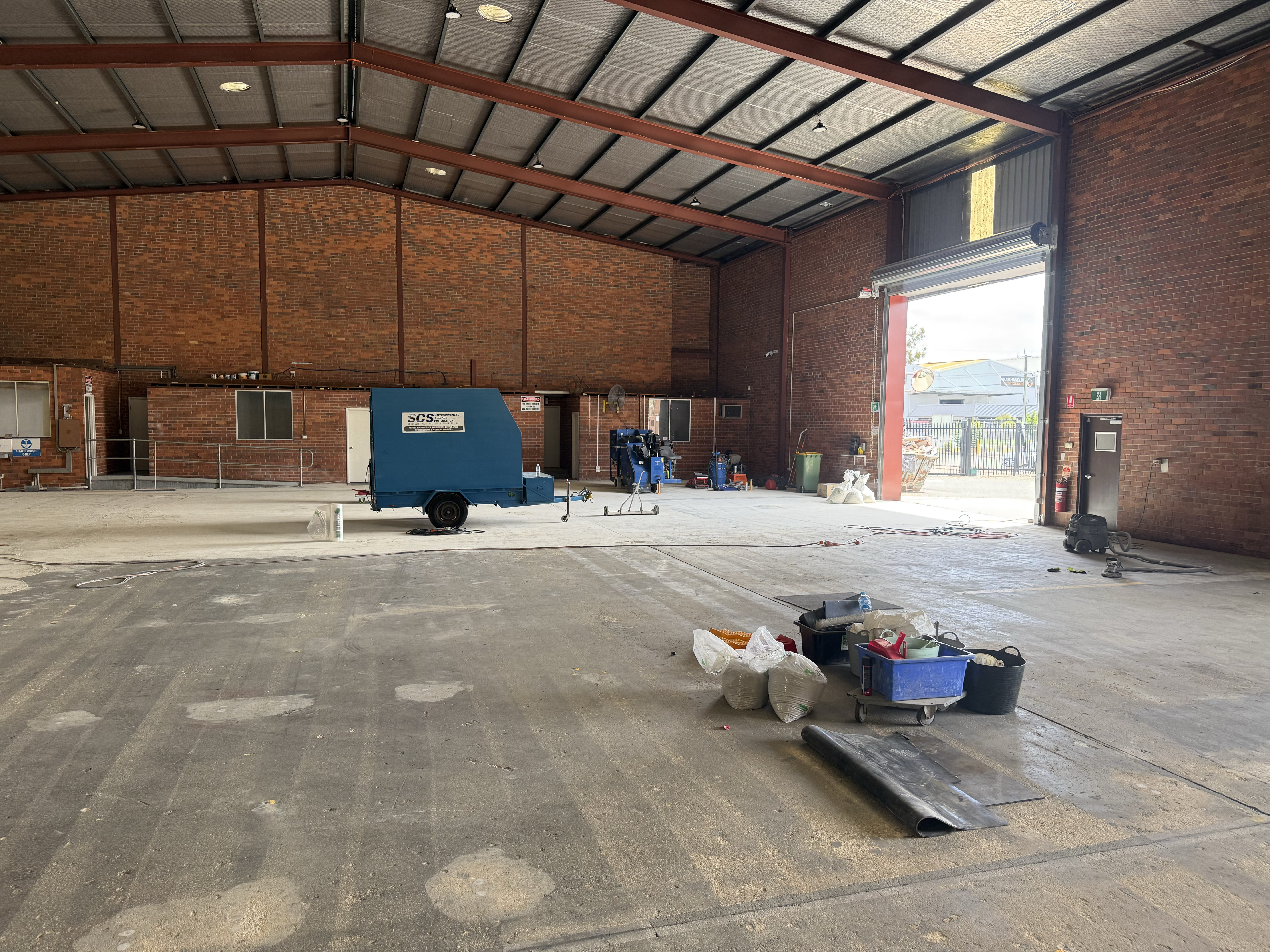 Specialist Contracting Services crew applying epoxy flooring after concrete surface preparation in a Perth factory workshop