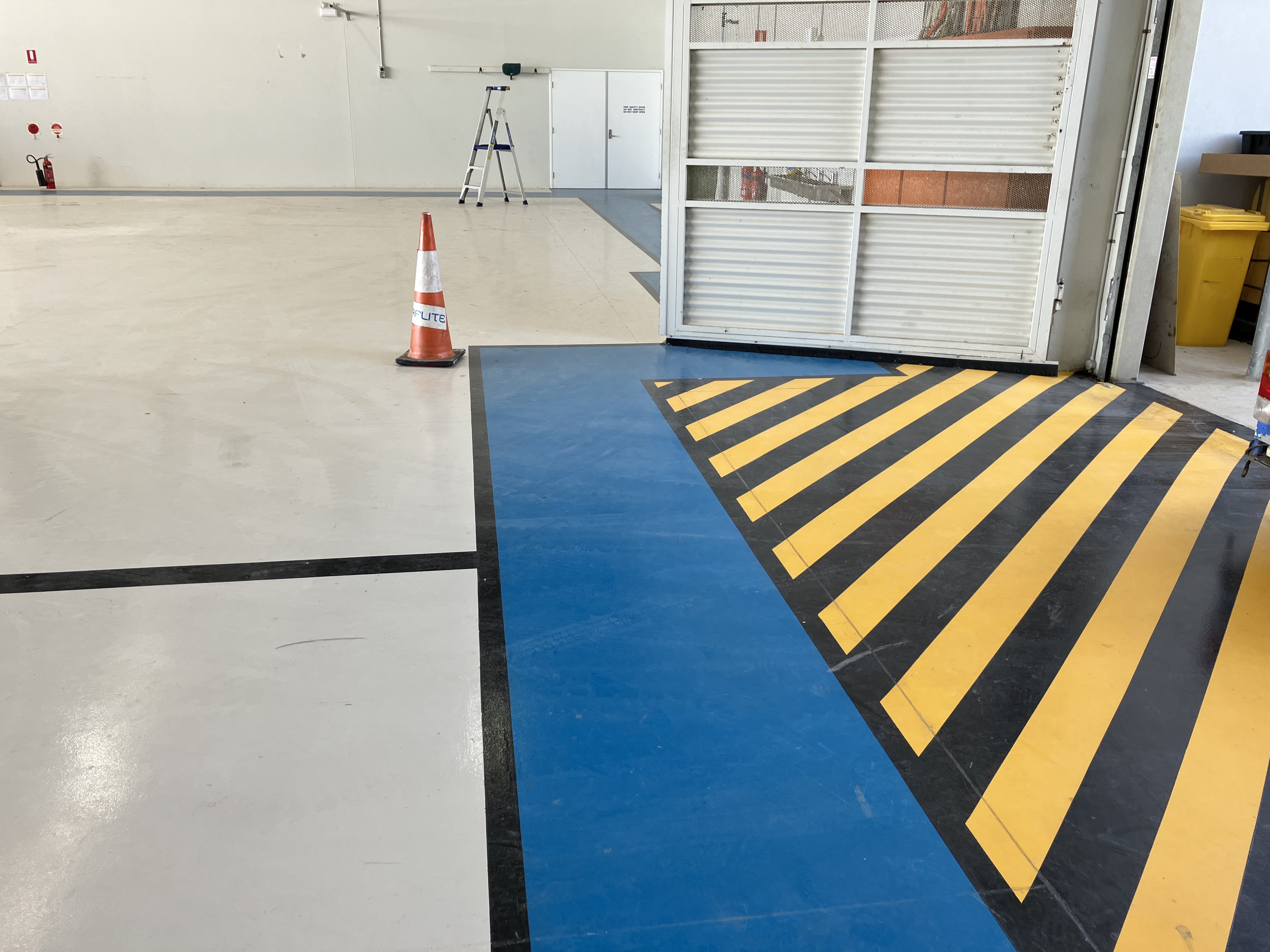 Operator using large blue shot blasting machine to prepare concrete deck under scaffolding on an industrial project in Perth